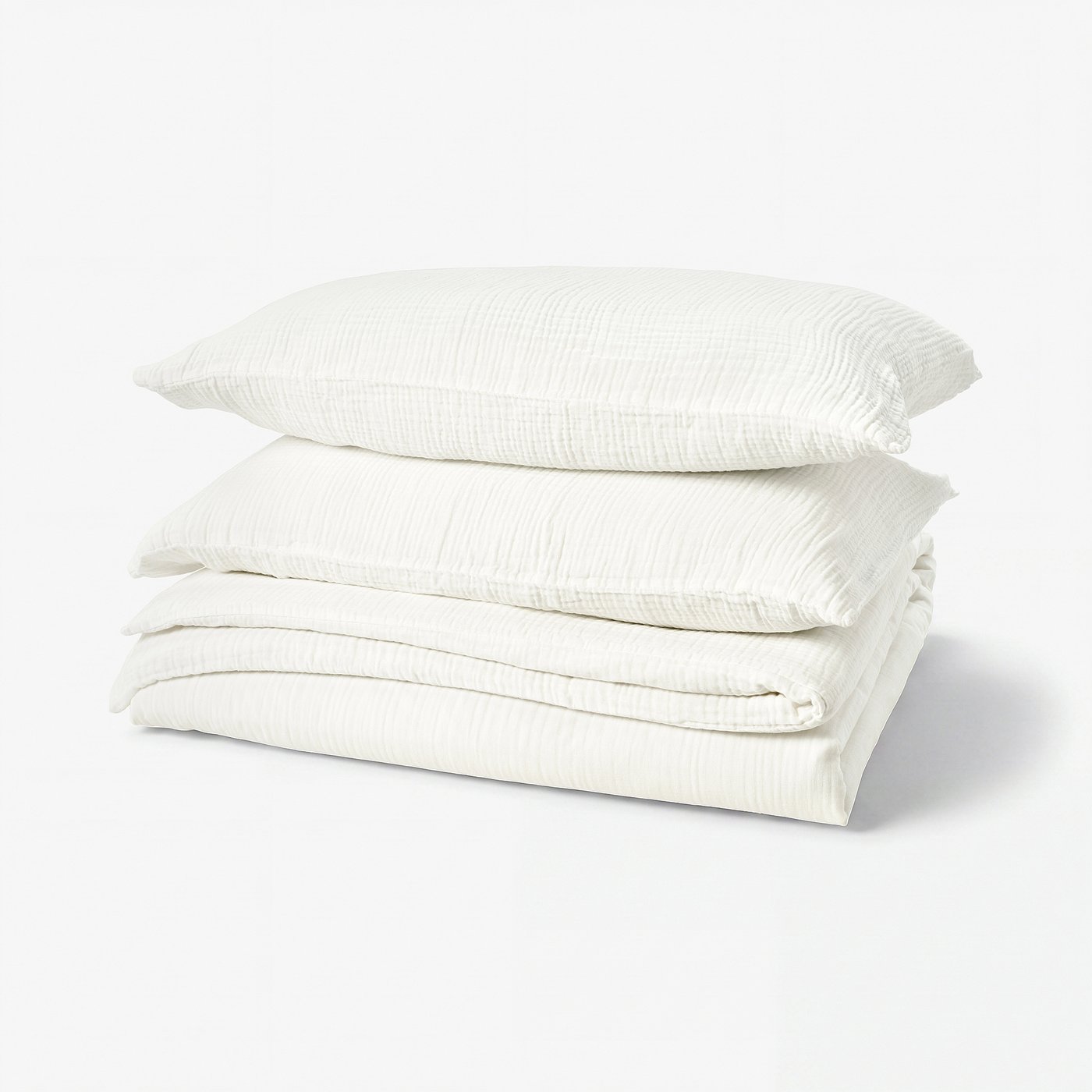 Stack of white, organic cotton bedding, including duvet cover and pillowcases, neat and folded, feature soft, wavy texture.