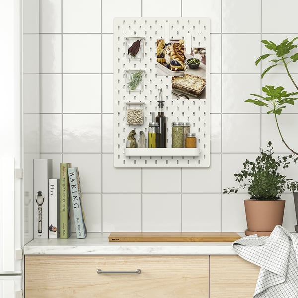 Kitchen pegboard organiser with spice jars, herbs, and photos.