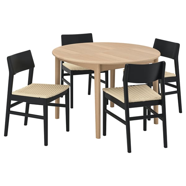 A modern dining set with a light wooden round table and four black chairs with woven seats.