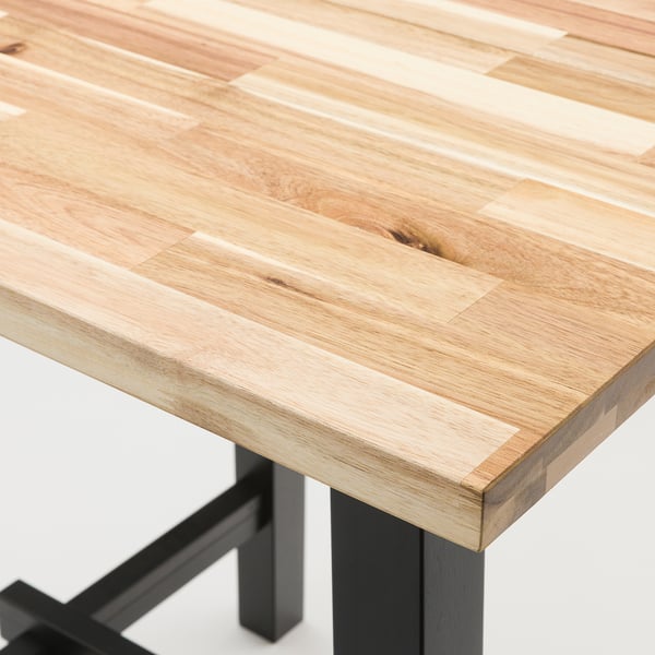 Close-up view of a sleek, wooden tabletop with visible grain texture and a smooth finish, supported by sturdy black legs.
