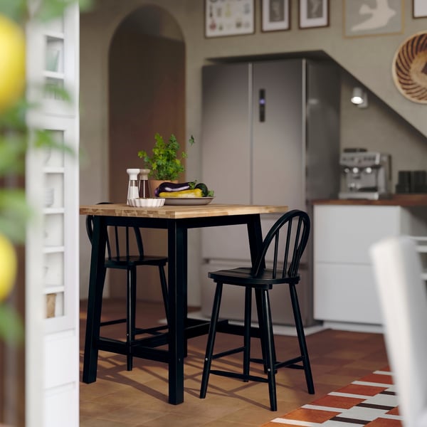 Small black wooden bar table and chairs in kitchen.