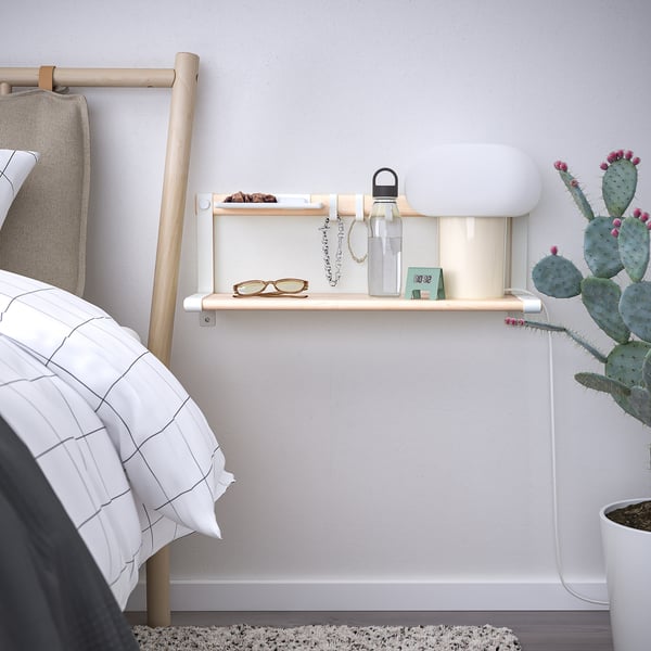 SKOMAKARE wall shelf in light wood holds glasses, keys, & bottle. Mounted beside bed with cactus plants and hooks. Minimalistic and functional.