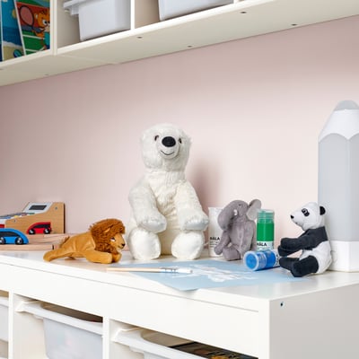 A childs desk with stuffed animals and drawers. A prominent white polar bear sits among them, looking playful and cuddly.