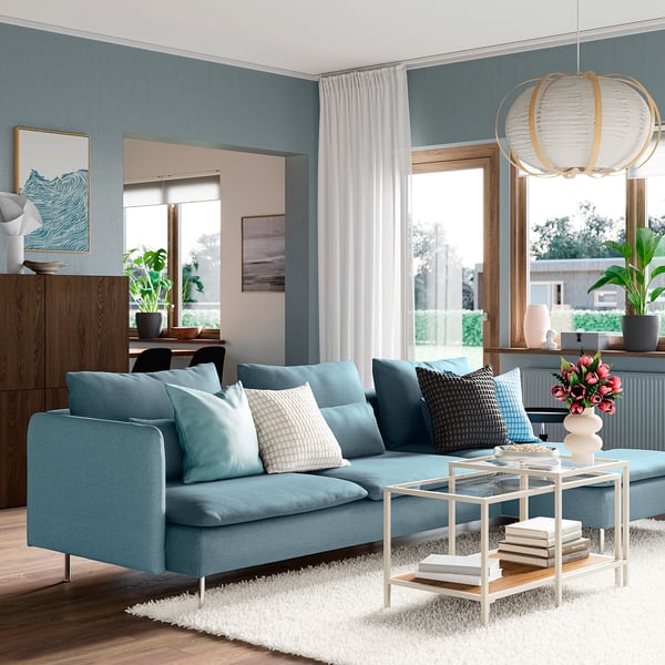 Modern living room with SÖDERHAMN light blue sofa, wooden cabinet, glass coffee table, and large windows.