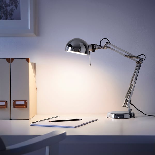 Modern silver lamp with adjustable arm, focused light, notebook, pen, ruler.
