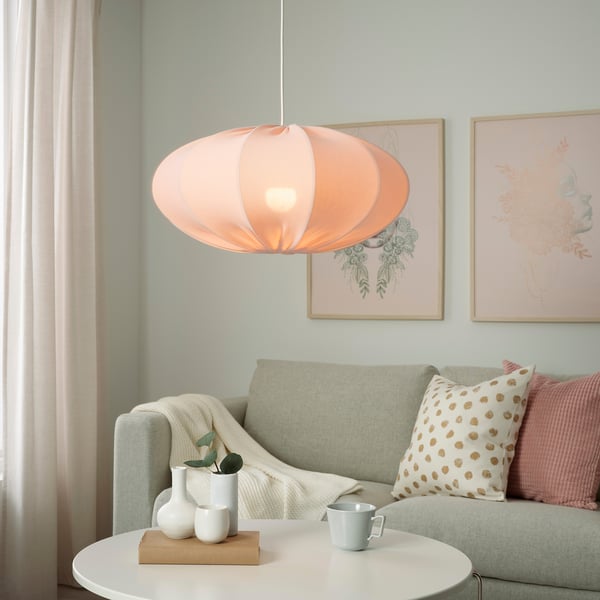 Modern living room with large orange pendant light, grey sofa with pillows, flower art, and teal walls.