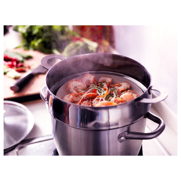 Silver pots with colourful food and steam, placed on a modern stove.