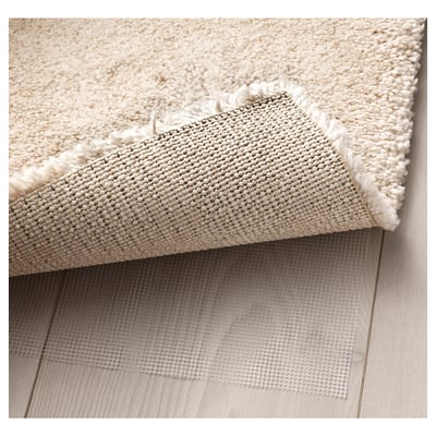 Thick, soft rug with mesh underlay. Edges show dense pile and anti-slip texture.