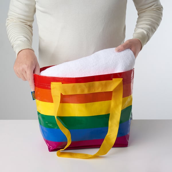 Person holding colourful, foldable bag.