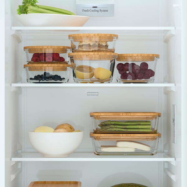 A well-organized fridge with adjustable glass shelves and air flow system, storing fruits and vegetables in clear containers.