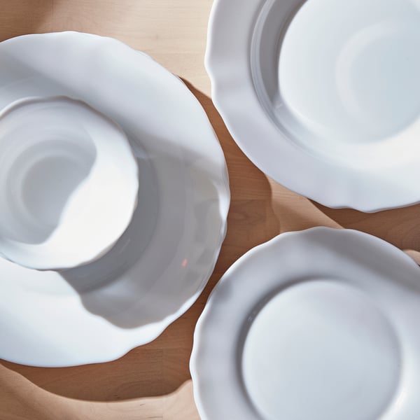 Three white dishes with wavy edges on a wooden surface, suitable for meals and parties.