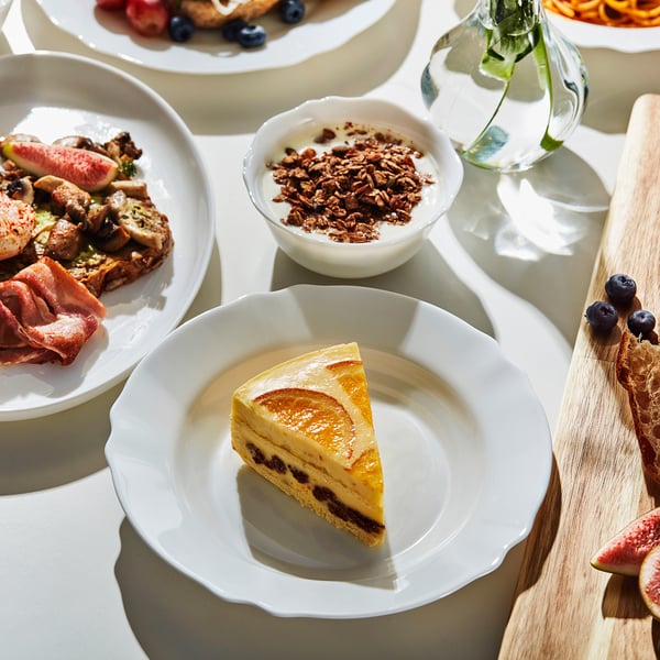 Plate of cake surrounded by dishes with various foods on a table, perfect for family dinners.