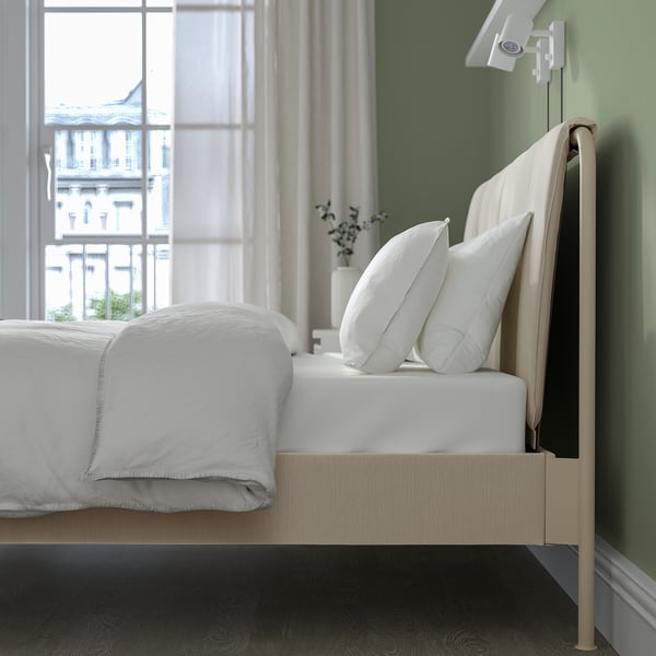 Modern upholstered bed by window, urban view, neutral bedding.