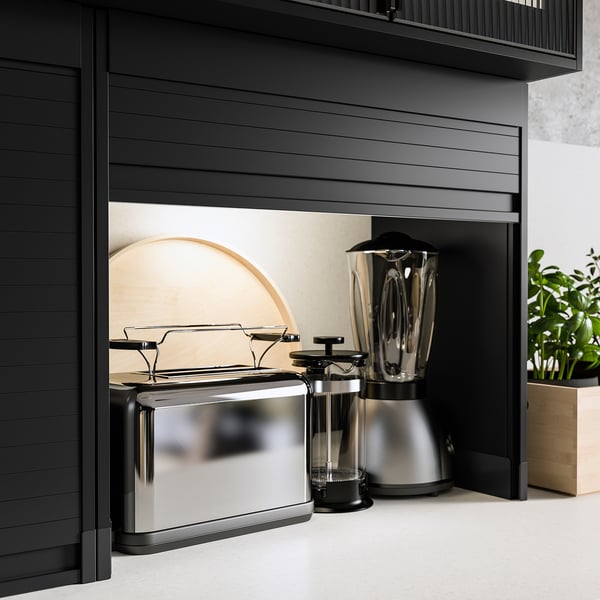 Modern black kitchen cabinet with silver appliances; toaster, blender, and coffee maker neatly stored inside.