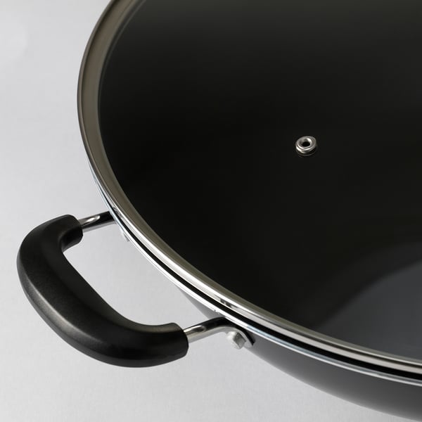 High-quality wok with black phenolic handle and glass lid, showing robust design and non-stick coating.
