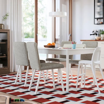 White dining table with grey chairs, red rug, smooth tabletop, wooden legs, large window.