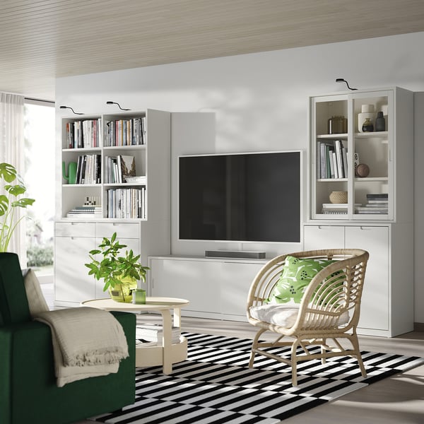 Off-white living room with TONSTAD furniture, wicker chair, and striped rug, decorated with plants.