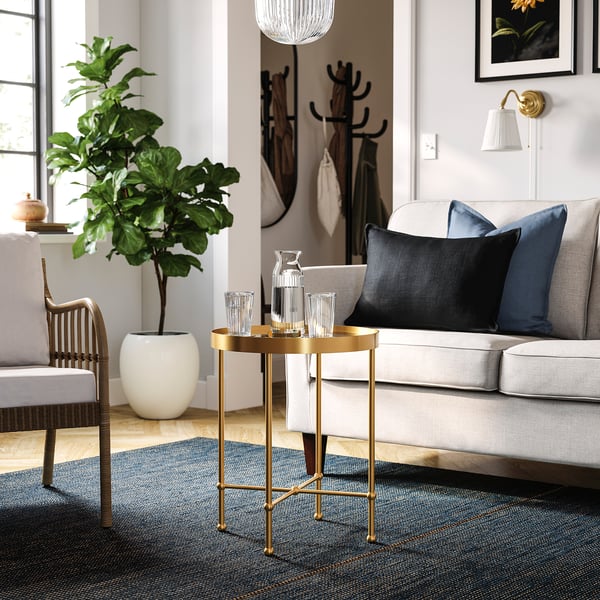 Stylish living room with gold side table, sofa, plant, and patterned carpet.