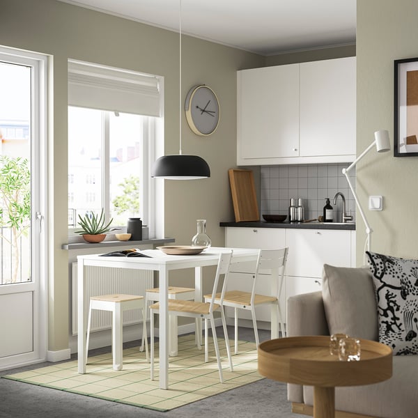 Modern kitchen & dining area with TRÄNNÖ stools, black lamp, plants, clock. Bright, minimalist style.