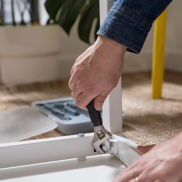 Person using hammer from TRIXIG toolbox, assembling furniture with a rubber mallet.