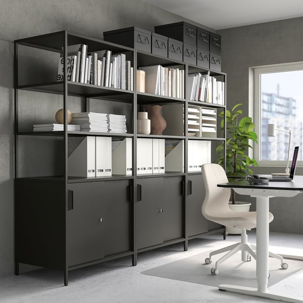 Modern black bookshelf with books, binders, decor, and office chair.
