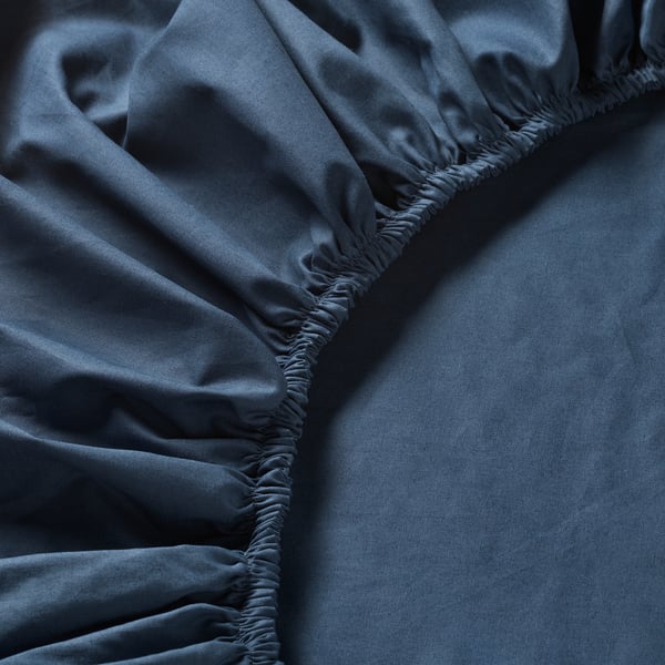 Dark grey bed sheet with intricate elasticated corners, smooth texture, tightly woven fabric.