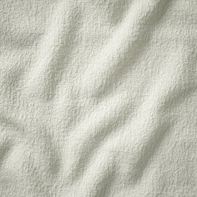 Close-up of soft, textured, white bouclé fabric, showcasing its plush and inviting quality.