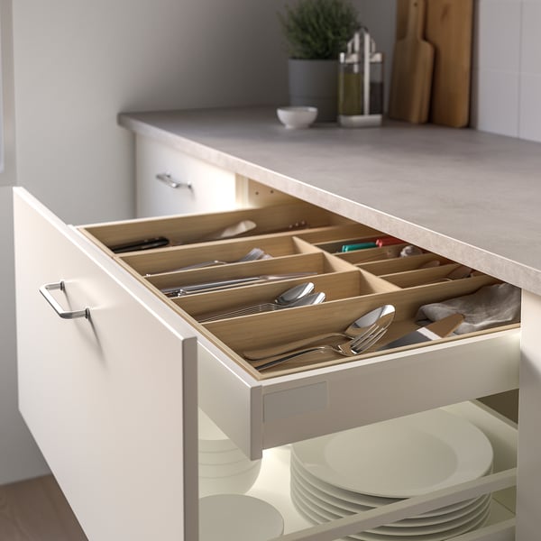 A kitchen drawer organiser holds cutlery in bamboo tray compartments, neatly arranged. It prevents scratches and slides out on plastic feet.