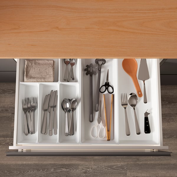 Organised kitchen drawer with UPPDATERA cutlery tray, holding forks, knives, spoons, and utensils neatly in compartments.