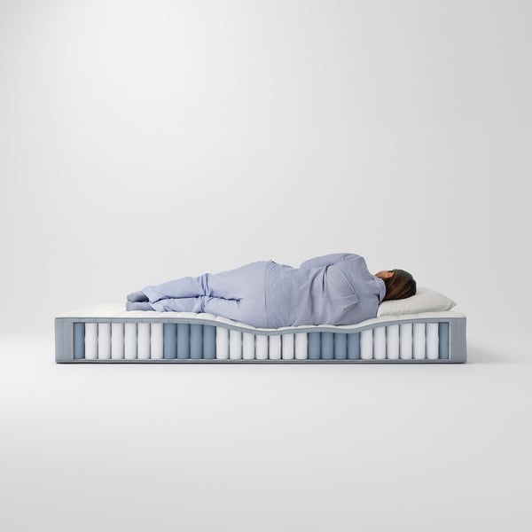 A person sleeping on a light blue VALEVÅG mattress, which has white springs.