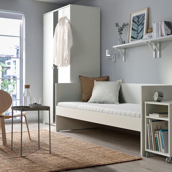 Minimalist living room with white VIHALS daybed, side table, bookshelf, and decor. Bright, airy, with natural light.