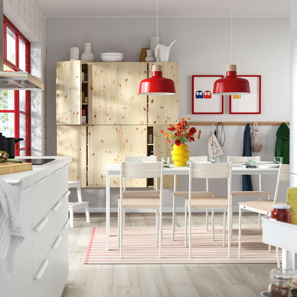 Modern kitchen with white cabinets, red lights, colourful decor, and extendable table set.