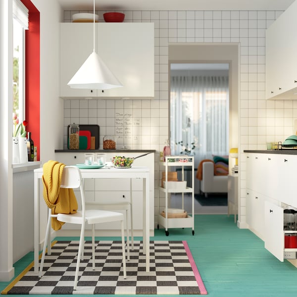 Bright kitchen with white VIHALS table and chairs, a yellow blanket, and colourful rug. Modern design with minimalist style.