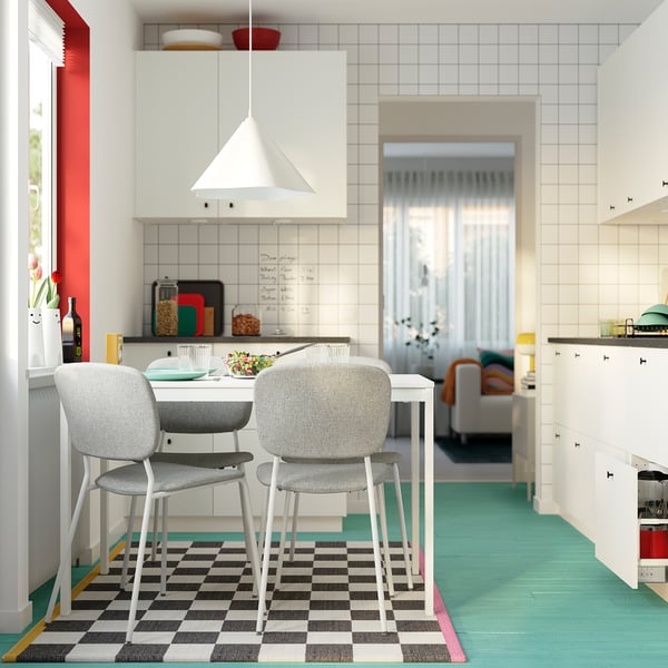 Modern kitchen with white extendable table, grey ergonomic chairs, and black-and-white rug.