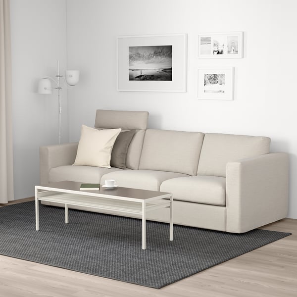 Modern living room with grey VIMLE sofa, coffee table, dark rug, art, and floor lamp.