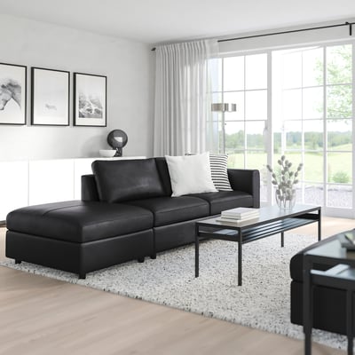Black VIMLE sectional sofa with storage footrest, throw pillows, coffee table, large windows & rug.