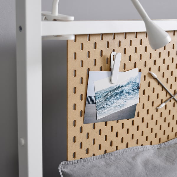 Pegboard with white clips holding waves, part of a white framed storage unit, clean and organised.