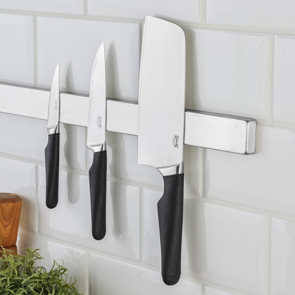 Magnetic knife rack holding three stainless steel VÖRDA knives with black handles against white tiled wall.