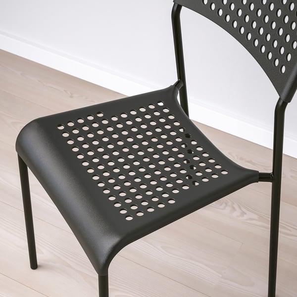 Black modern plastic chair with perforated design, stackable, durable, suitable for indoors.