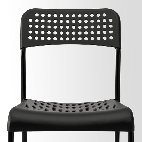 Modern black stackable chair with perforated seat and back for ventilation.