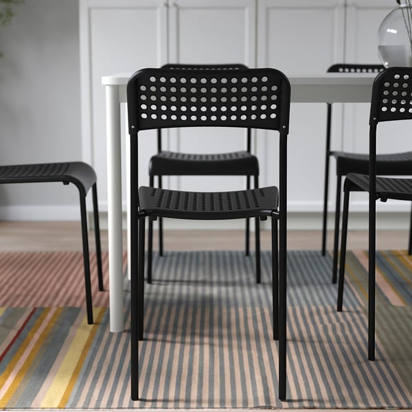 Stackable indoor plastic chairs in black, arranged on a striped rug.