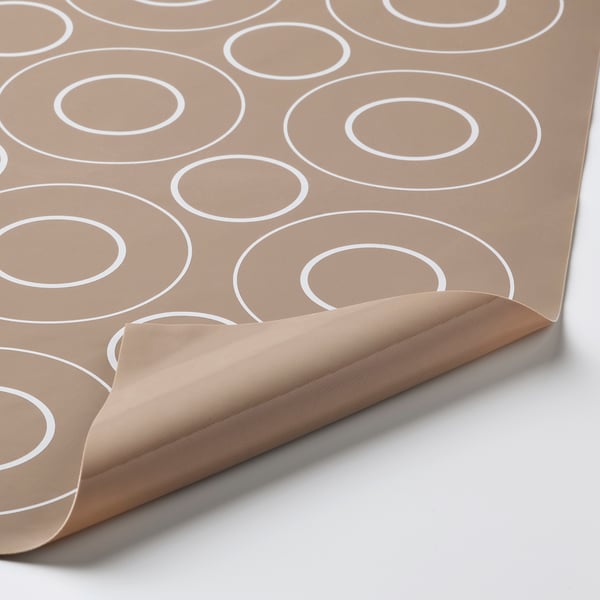 Brown baking mat with white circle patterns, folded corner showing texture.
