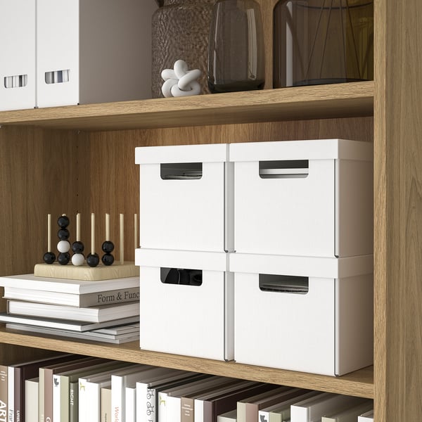Wooden shelves holding white storage boxes and books. Organised home office setup.