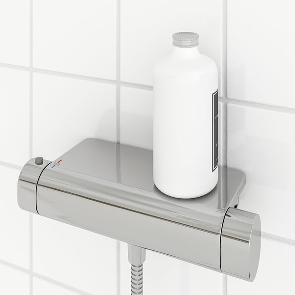 A modern chrome thermostatic shower mixer with a built-in shelf holding a bottle. It a safety stop at 38°c and a cold touch surface.