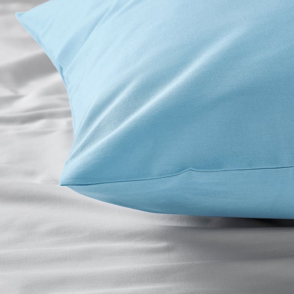 A close-up of a smooth, light blue pillowcase on a bed, highlighting its soft texture and quality.