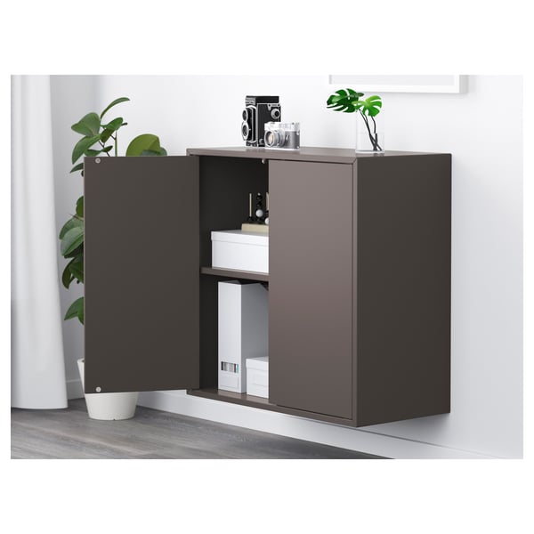 Modern dark cabinet with open door showing shelves, decorations, and plant.
