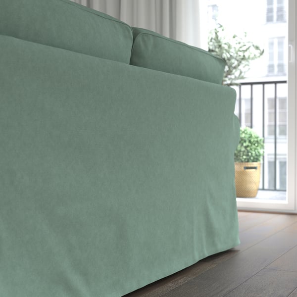 A cosy, turquoise EKTORP sofa near a window, offering a comfortable, inviting seating with thick cushions.