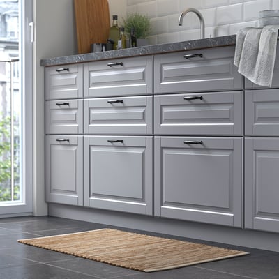 Modern kitchen with grey cabinets, sink, and jute rug.