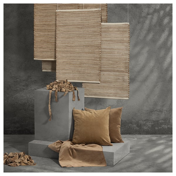 Modern interior decor with beige woven shades, brown pillows on grey blocks, textured grey wall.