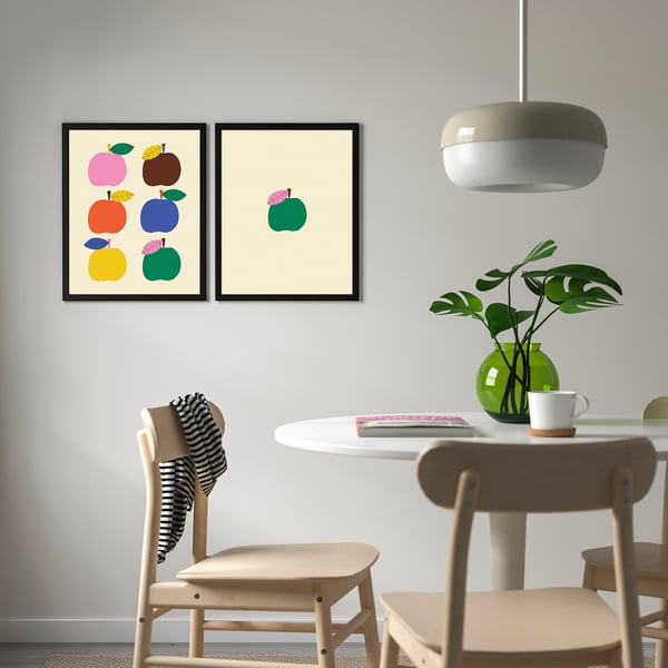 Colourful fruit prints above dining table with chairs, plant, and cup.